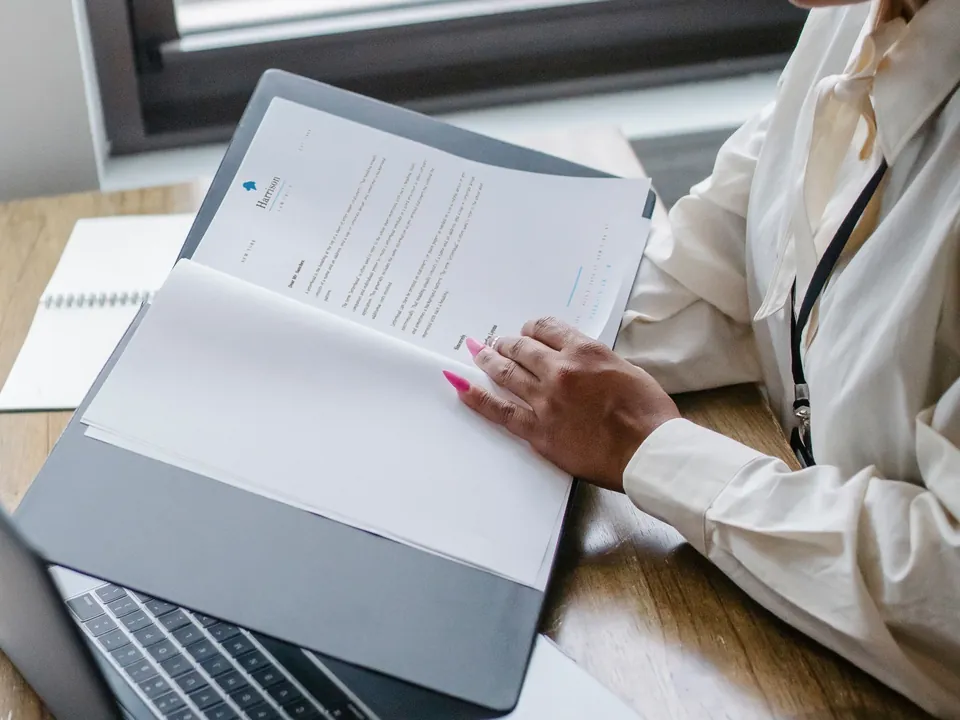 Professional reviewing documents beside a laptop