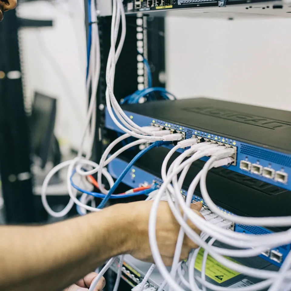 Technician connecting cables to rack-mounted network equipment
