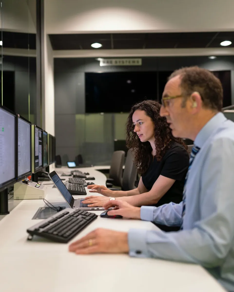 Two engineers working at a multi-screen workstation