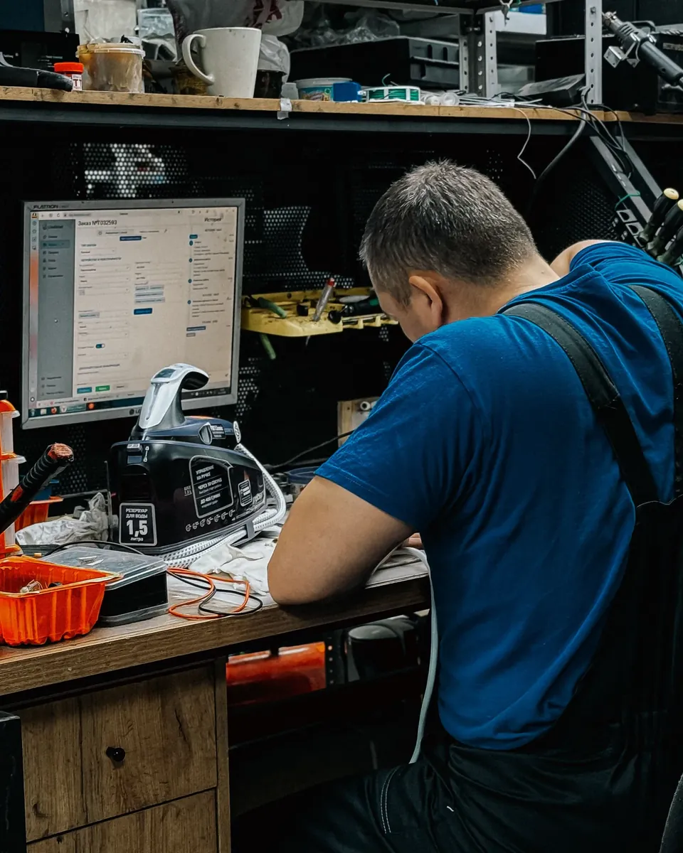 Technician working on computer equipment at a workshop desk